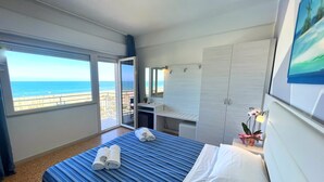 A hotel room with a bed, a desk, a wardrobe, and a balcony with a view of the sea. - Hotel Los Angeles - Frontemare (Riccione)