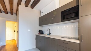 Une cuisine moderne avec des meubles gris, un four en acier inoxydable et un plan de travail sur lequel se trouve une machine à café.