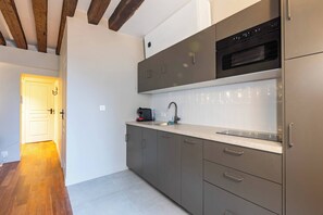 A modern kitchen with grey cabinets, a stainless steel oven, and a countertop with a coffee maker. - Élégant 3 chambres climatisé en plein Marais (Paris)