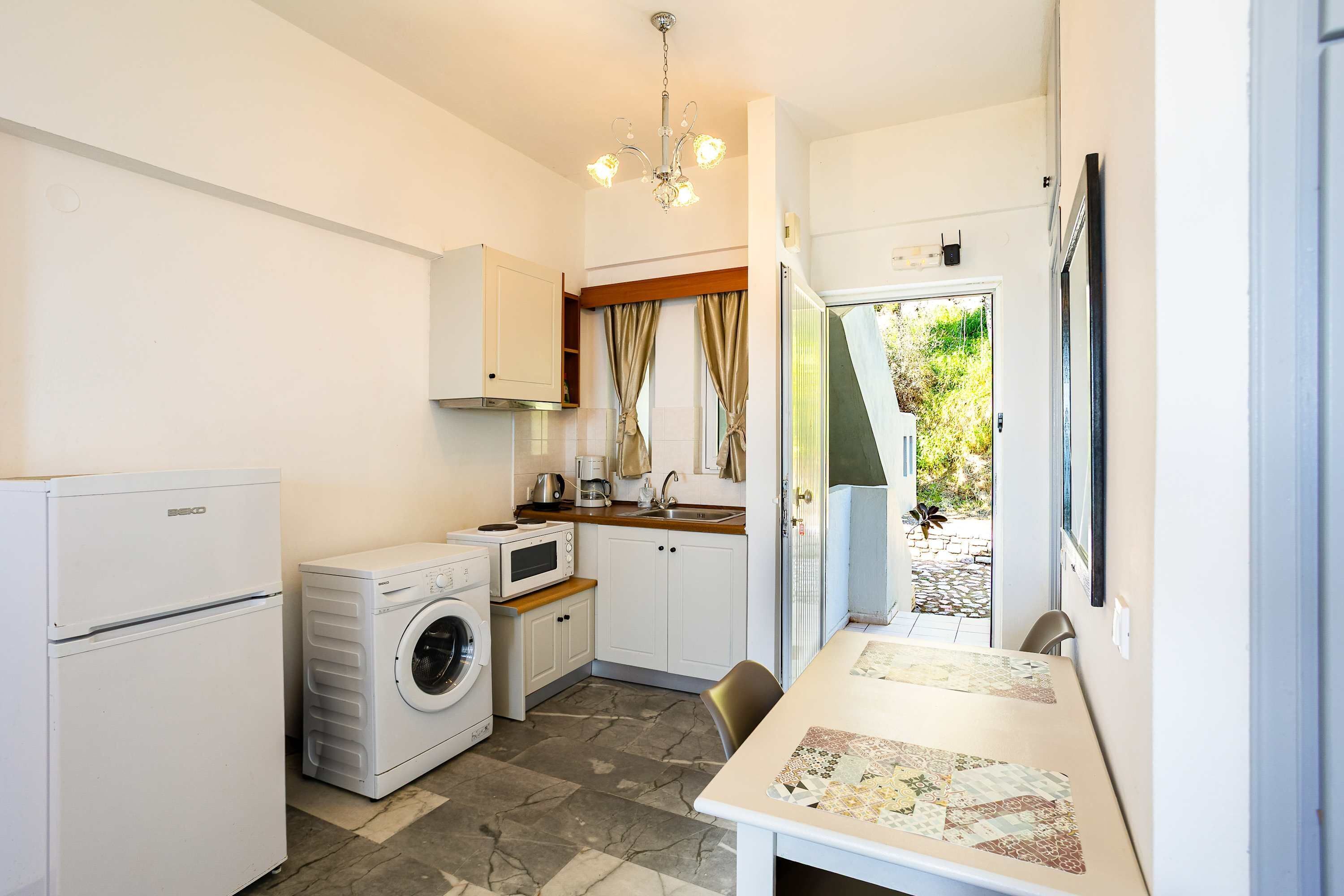 Une cuisine compacte équipée d’un lave-linge, d’un four à micro-ondes et d’un coin repas avec une table.