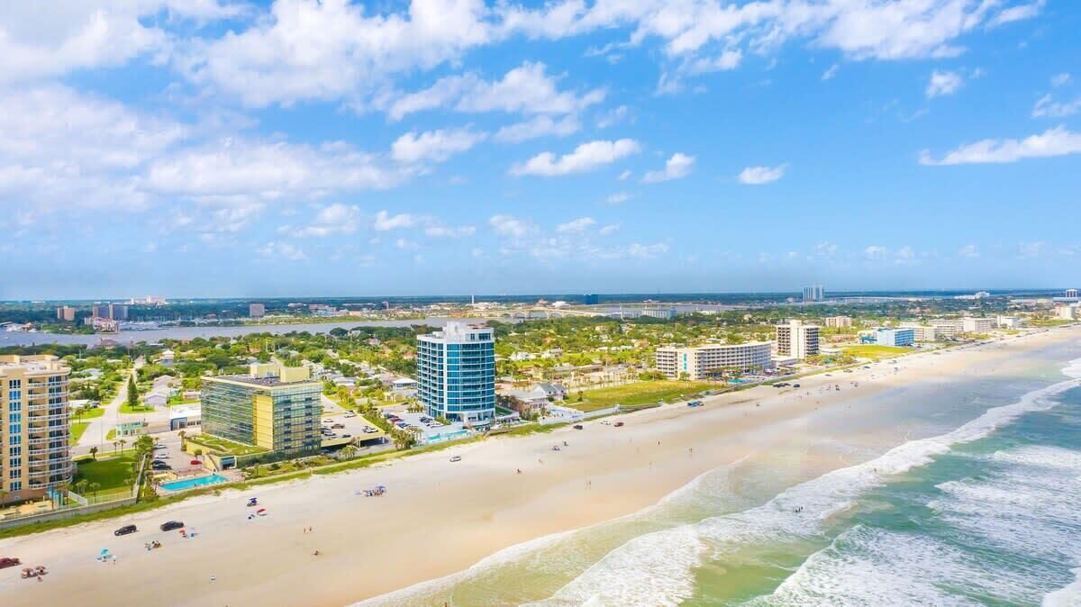 Un paysage urbain côtier avec une plage, des immeubles de grande hauteur et un ciel dégagé.