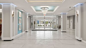 A spacious lobby with a modern chandelier, a glass door entrance, and a tiled floor. - Beach Studio With Partial Water Views Sundeck Pool (Daytona Beach Shores)