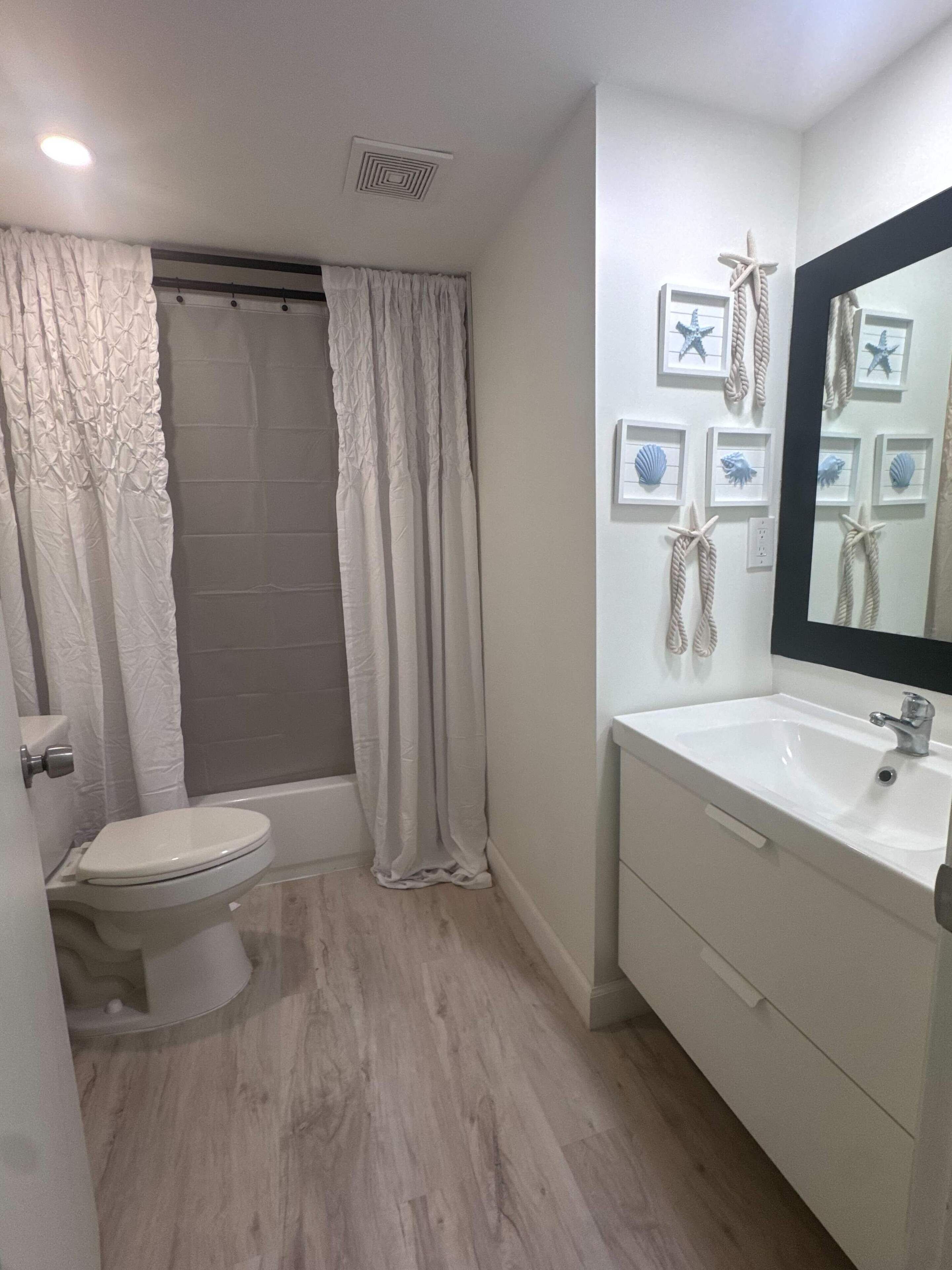Une salle de bain comprenant des toilettes, une baignoire et un lavabo avec un miroir.