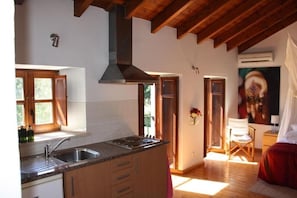 A kitchen with wooden beams, a large island with a sink, and a painting on the wall. - Romantic Hideaway with Terrace and Garden View in Bensafrim (Faro)