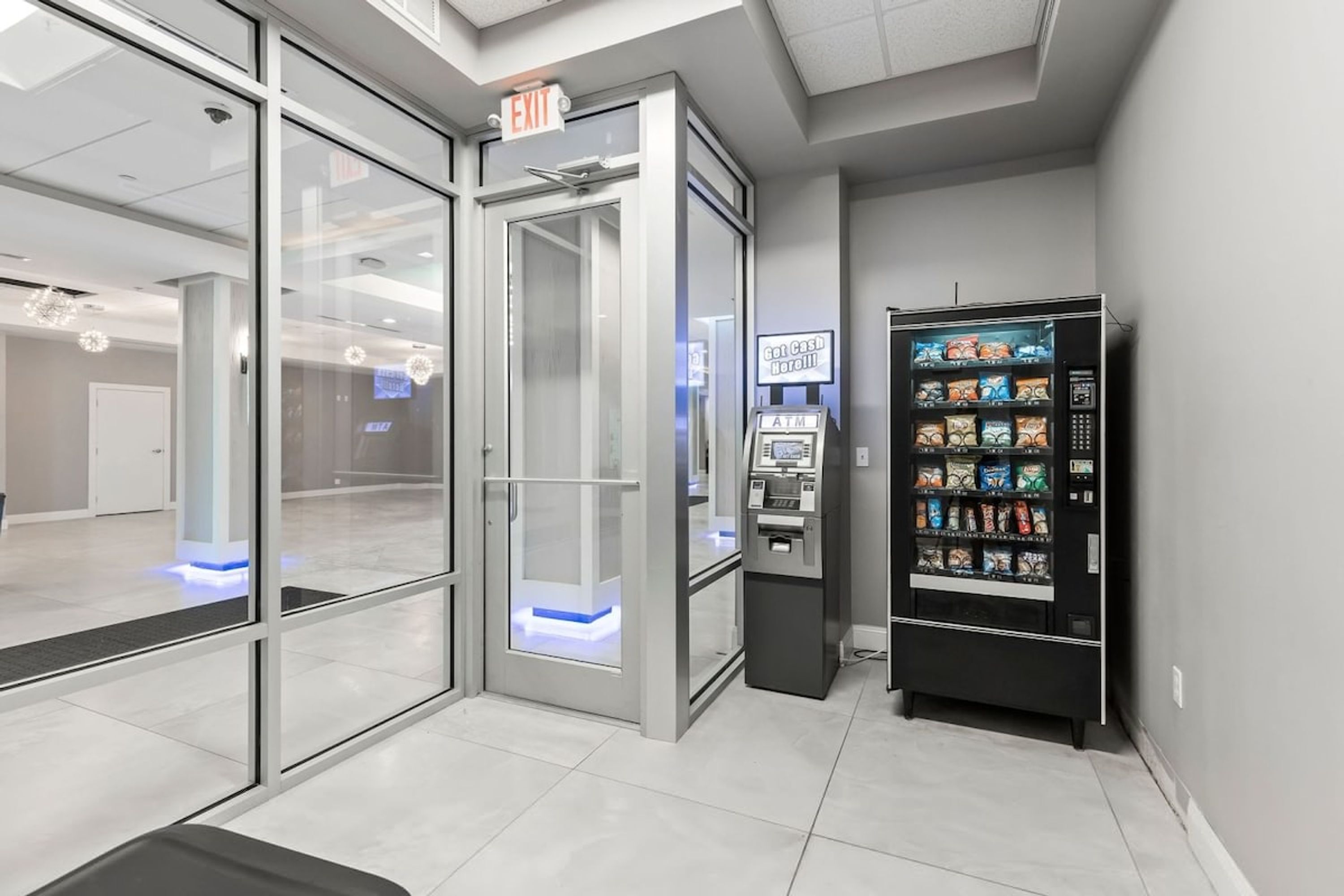 Eine moderne Lobby mit Glastür, Geldautomat und Verkaufsautomaten.