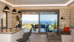 En moderne stue med et køkkenområde, et spisebord og havudsigt.