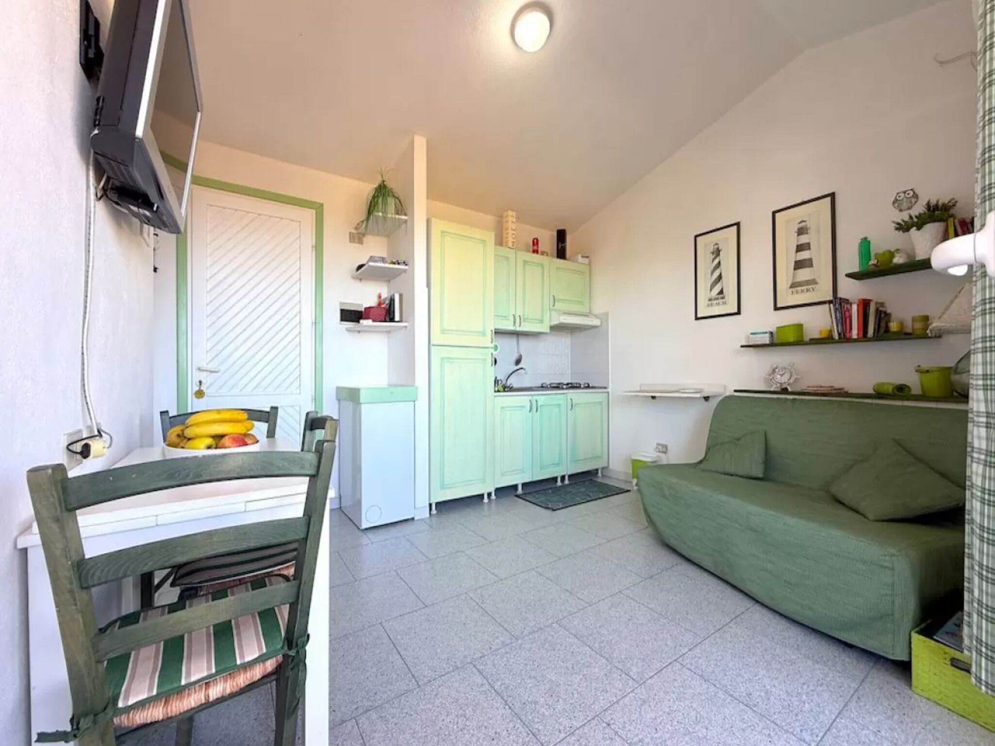 Ein kompakter Wohnbereich mit Essplatz, Küchenzeile und einem grünen Sofa.