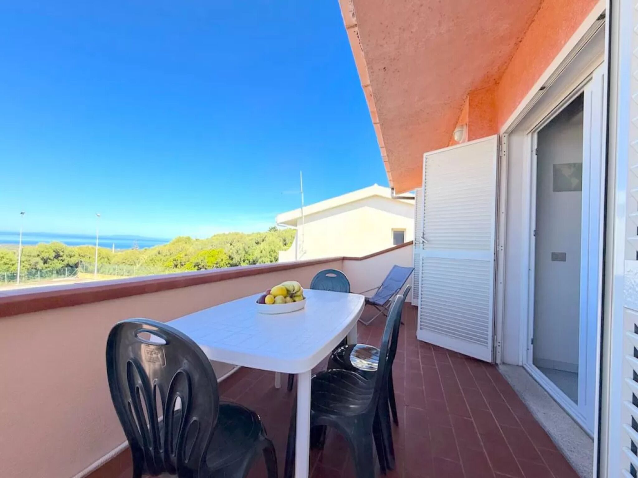 Ein Balkon mit Tisch, Stühlen und einer Obstschale.