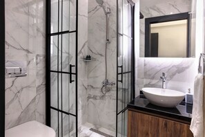 A bathroom with a glass-enclosed shower, a white sink, and a wooden vanity. - Room-gorgeous Hotel Roomg (Istanbul)