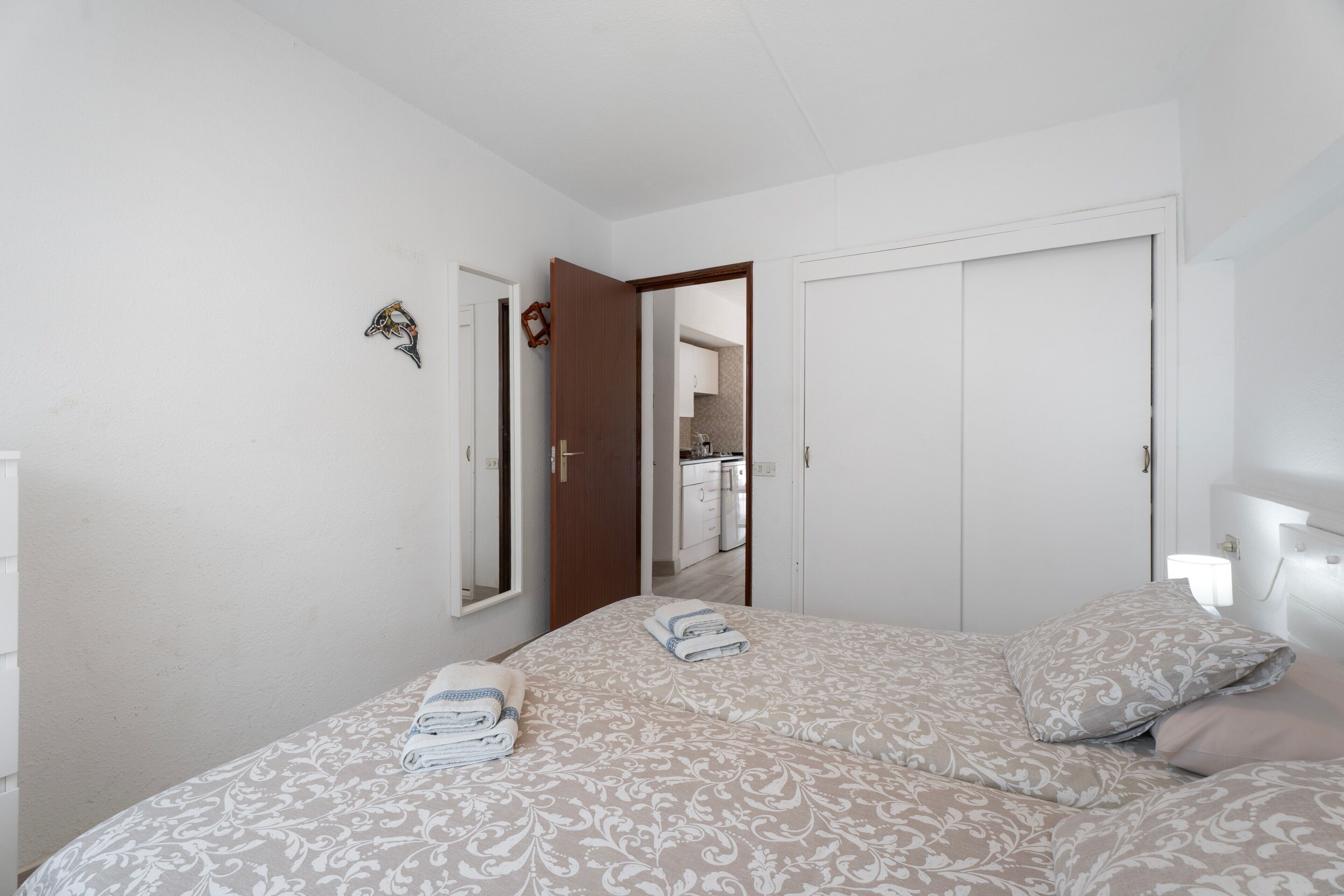 A bedroom with a bed, a door, and a mirror.