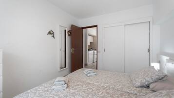 A bedroom with a bed, a door, and a mirror.