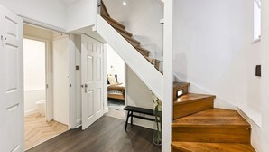 A staircase with wooden steps and a glass railing leading to a bedroom. - Argyl | Phillimore Walk 5 Bed Townhouse (Greater London)