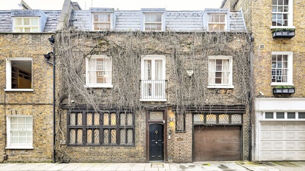 A brick building with three windows, a dark door, and a garage door. - Argyl | Phillimore Walk 5 Bed Townhouse (Greater London)