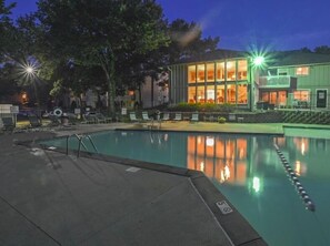 A swimming pool with a clear water lane, surrounded by lounge chairs and a building with large windows. - Cozy Luxe Stay in Kansas City (Kansas City)
