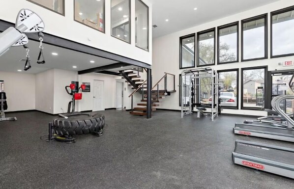 A modern gym with treadmills, a stair climber, and weightlifting equipment. - Cozy Luxe Stay in Kansas City (Kansas City)