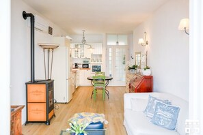 A compact living space with a kitchenette, a dining area, and a seating area with a sofa and decorative pillows. - JULIA'S PLACE by Design Studio (Perledo)