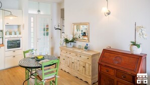 Een keuken met een eettafel, stoelen, een kast en een spiegel.