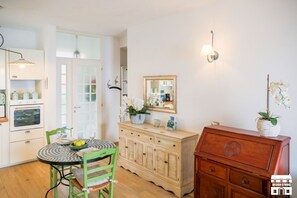 A kitchen with a dining table, chairs, a cabinet, and a mirror. - JULIA'S PLACE by Design Studio (Perledo)