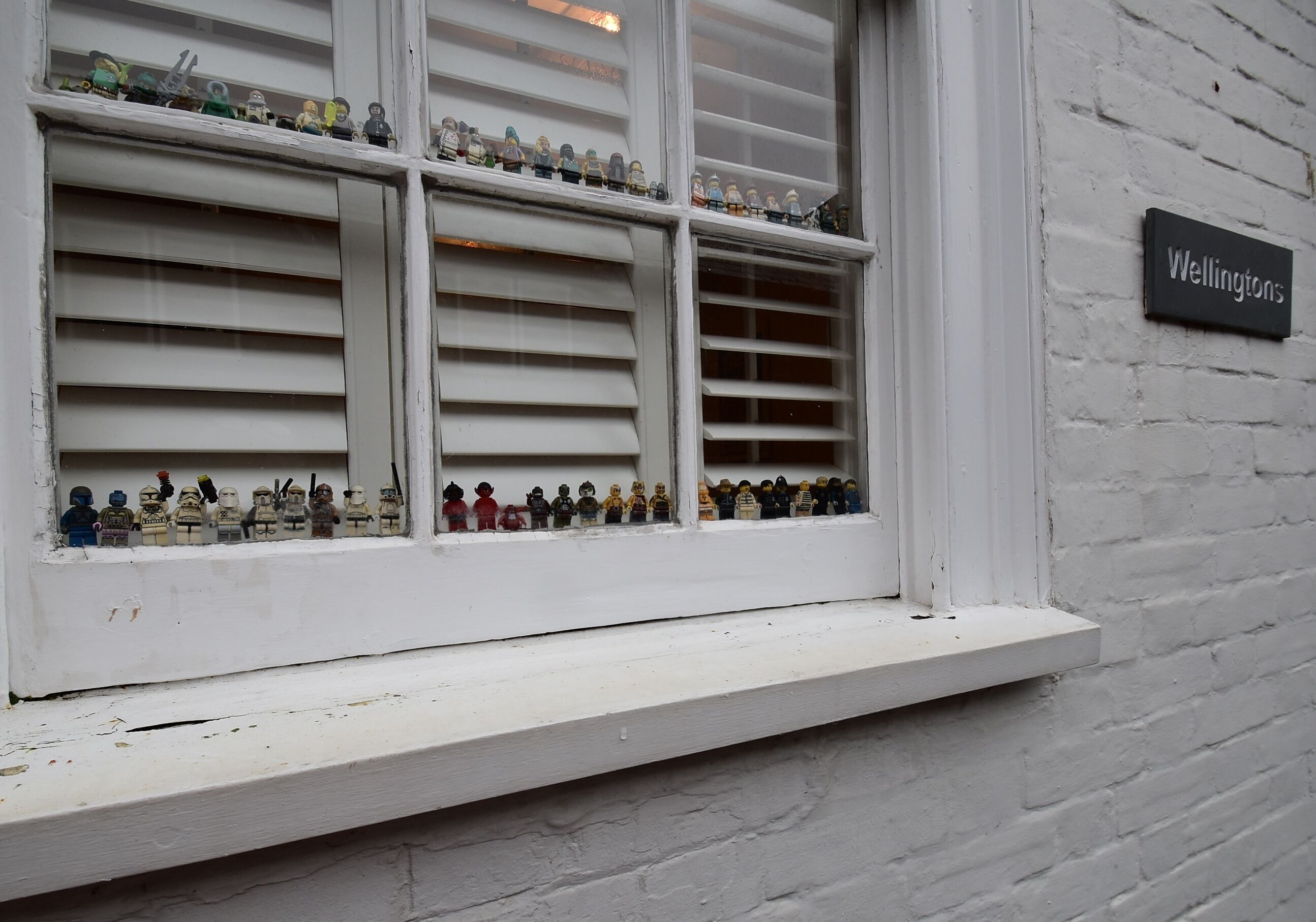 A window with multiple shelves displaying various figurines.