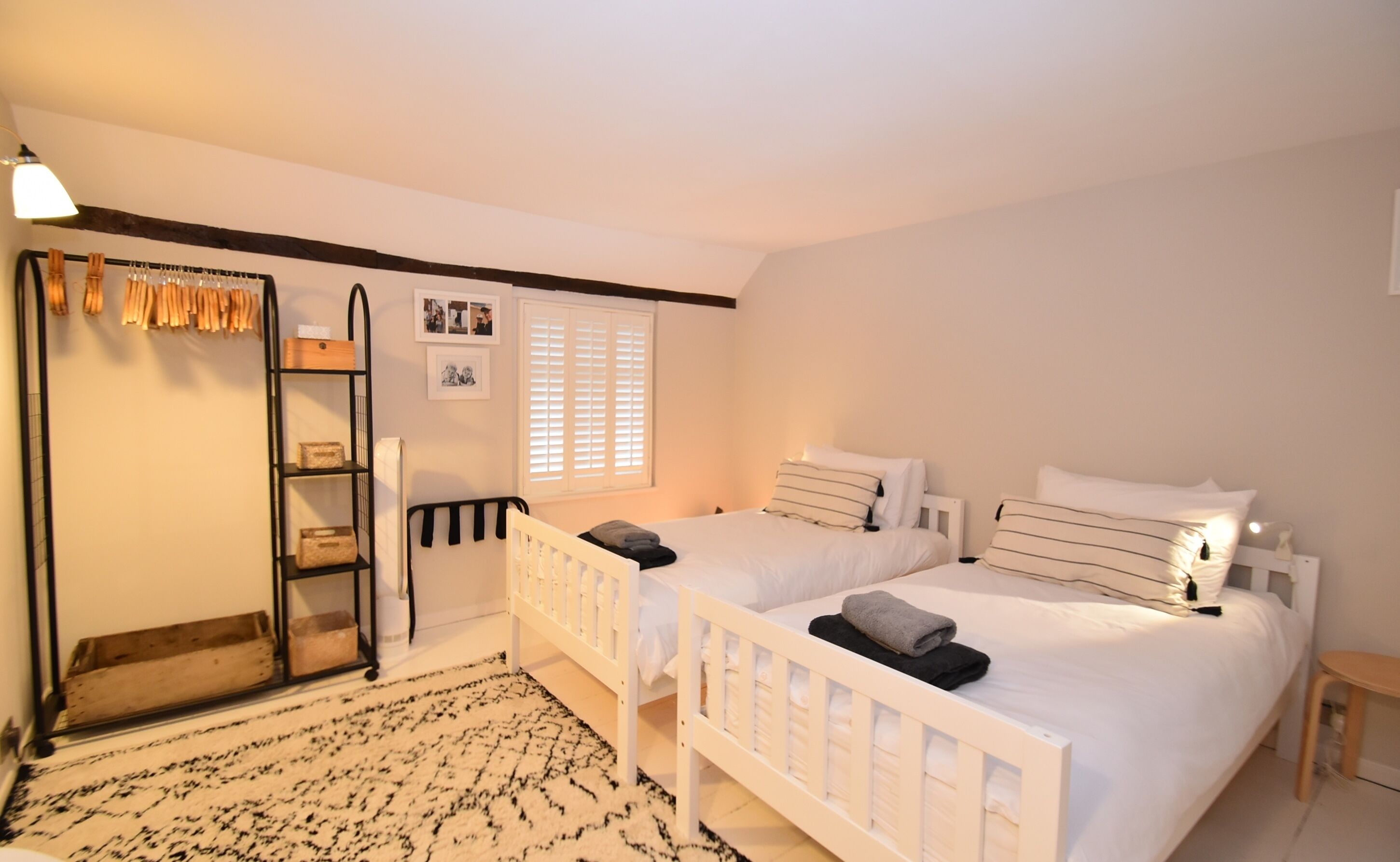 Un dormitorio con dos camas individuales, un armario, un espejo y una ventana con persianas.