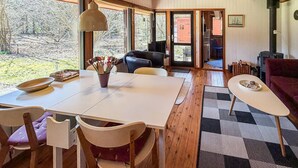 Ein Essbereich mit Tisch, Stühlen, einer Blumenvase und Blick ins Freie.