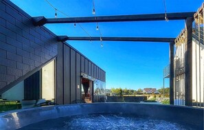 Ein modernes Gebäude mit einem von Glas umschlossenen Pool, einem überdachten Außenbereich und blauem Himmel.