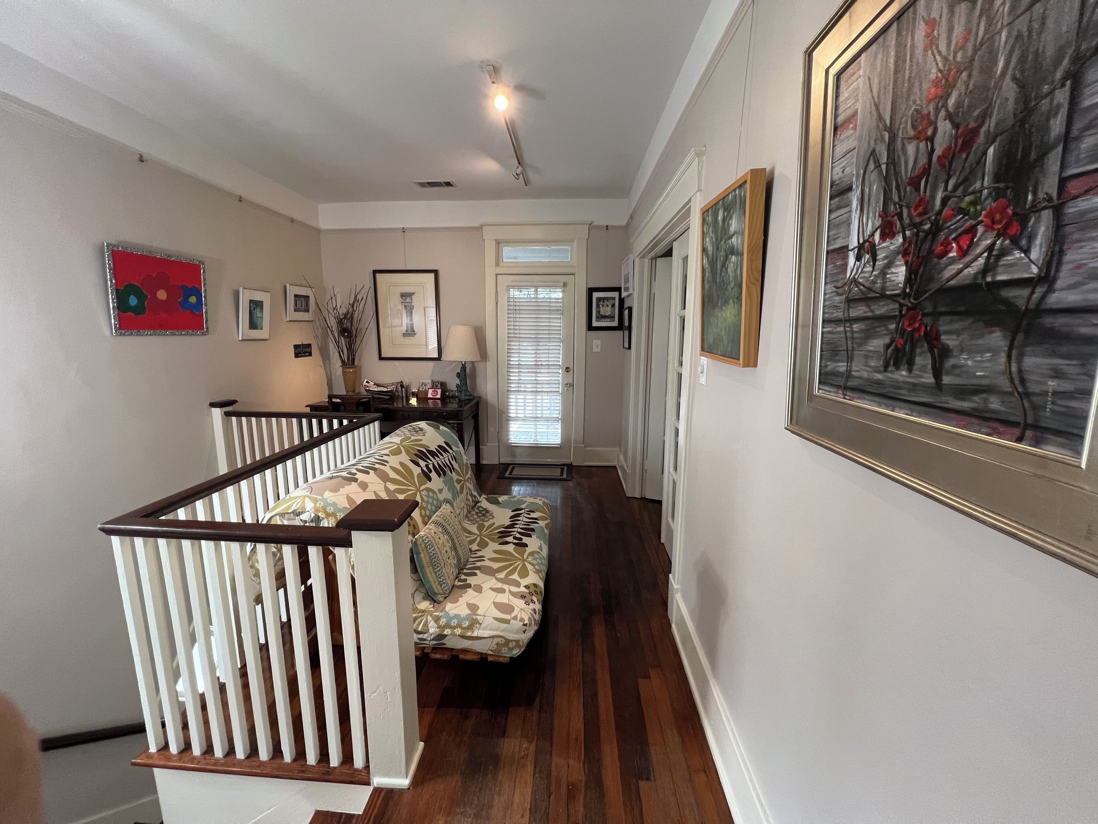 A hallway with a staircase, a sofa, and a door leading to another room.