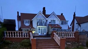A two-story house with a front entrance, a staircase, and a gated driveway. - 8-Bed Holiday Home (Sleeps 18): Direct Beach Access, Games Room, Bar & Parking (Skegness)