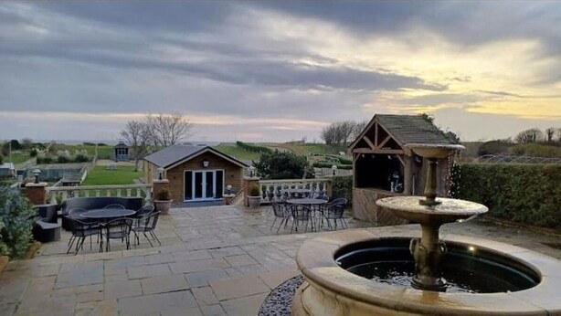 A patio area with outdoor seating, a fountain, and a small building with a door. - 8-Bed Holiday Home (Sleeps 18): Direct Beach Access, Games Room, Bar & Parking (Skegness)
