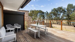 A wooden deck with a table and chairs, a bench, and a view of trees and a body of water. - Nanda Lake House: 2  BR, 1  BA Cottage in Bonnie Doon, Sleeps 8 (Bonnie Doon)
