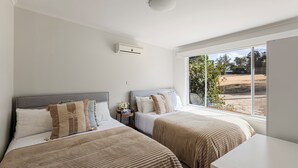 A bedroom with two beds, a bedside table with a lamp, and a window with a view of the outdoors. - Nanda Lake House: 2  BR, 1  BA Cottage in Bonnie Doon, Sleeps 8 (Bonnie Doon)