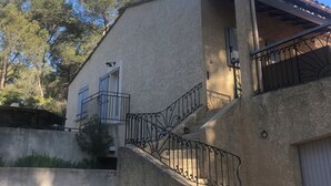 Ein zweistöckiges Gebäude mit einer Sandsteinfassade, einem Balkon mit schmiedeeisernem Geländer und einer Garagentür.