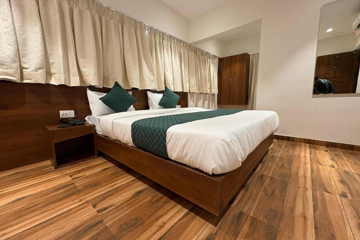 A modern bedroom with a wooden bed, a nightstand, a large mirror, and a wooden floor.
