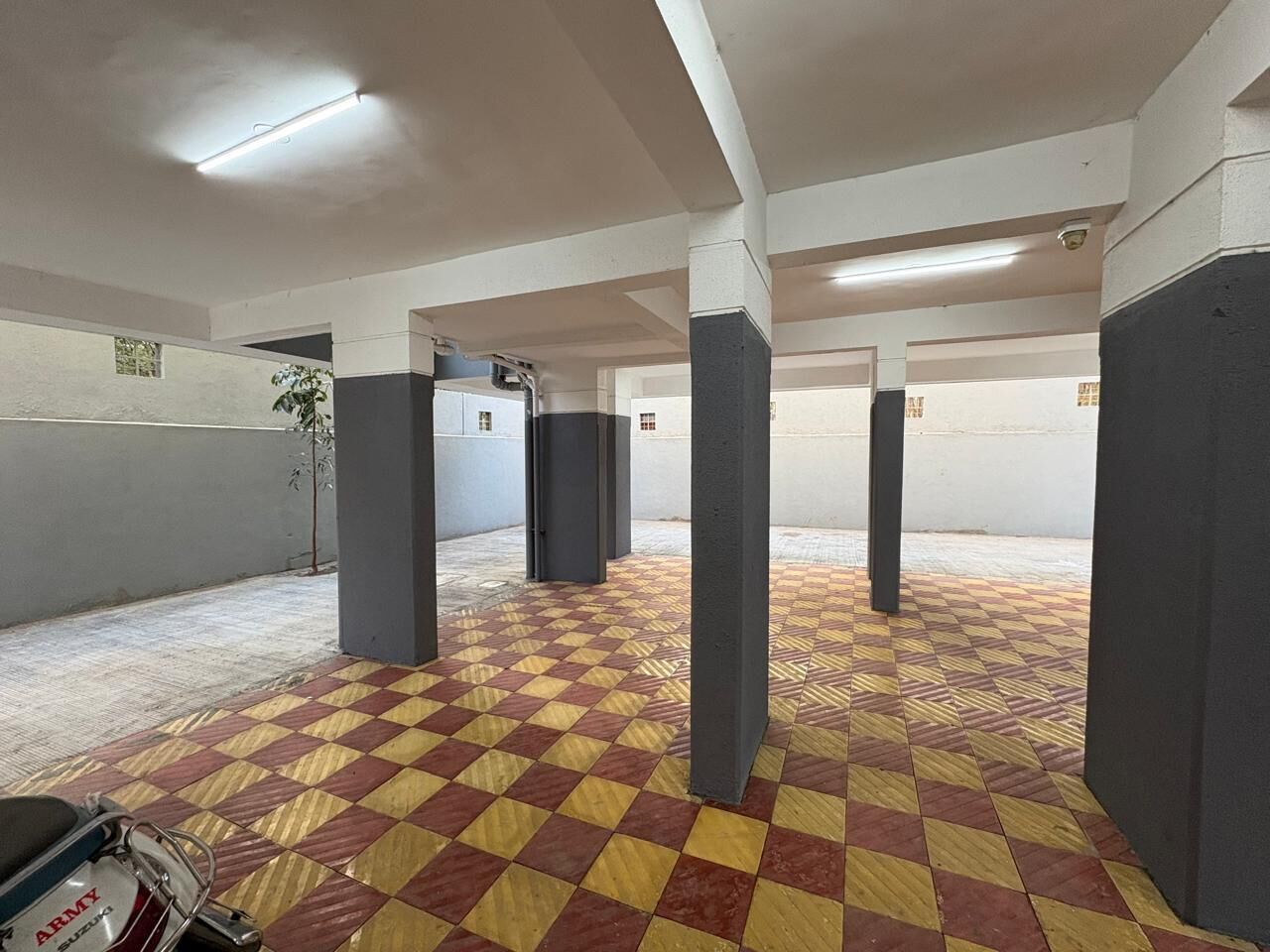 A spacious indoor area with a checkered floor, columns, and a motorcycle in the foreground.