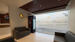 Eine moderne Lobby mit einer Sitzecke, einem Verkaufsautomaten und einem großen Fenster mit Blick nach außen.