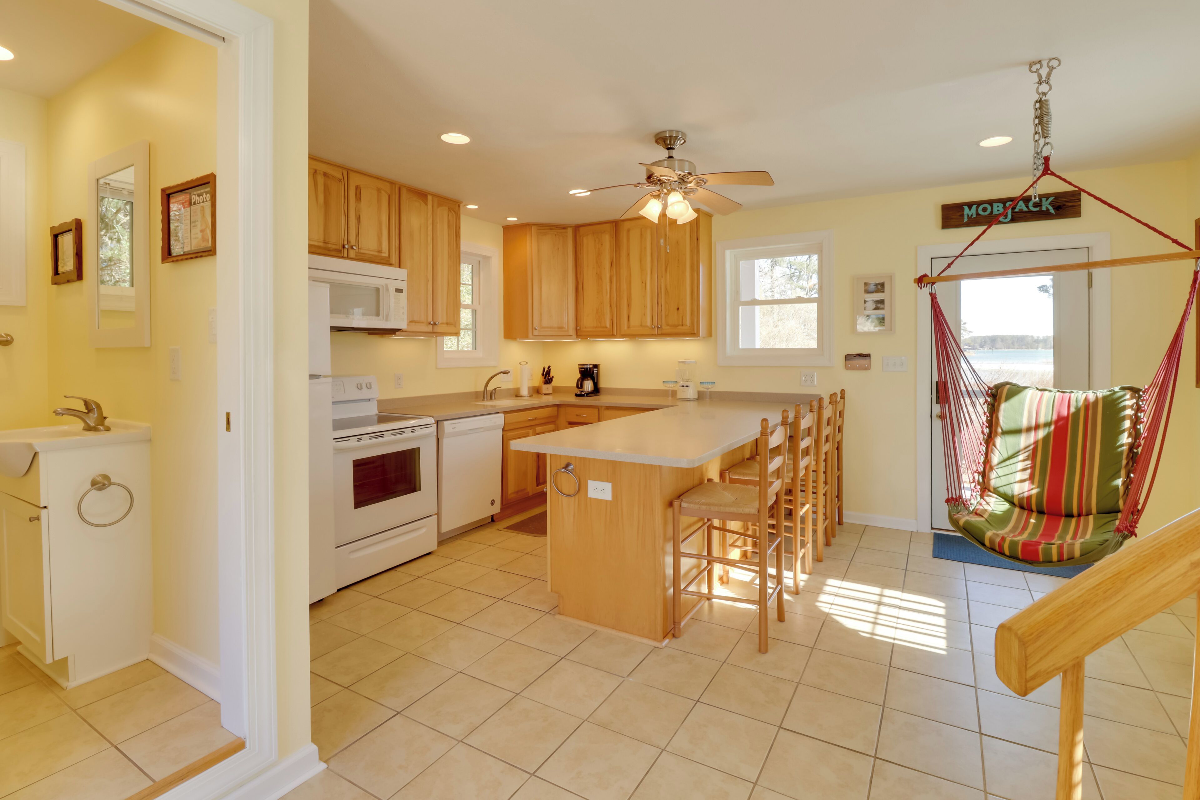 A modern kitchen with wooden cabinets, a central island, and a hanging chair.