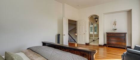 A bedroom with a bed, dresser, and a staircase leading to another room.