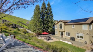 A residential backyard with a patio, a large tree, and a house with solar panels. - Fairfield Wine Country Getaway w/ Backyard Oasis! (Fairfield)