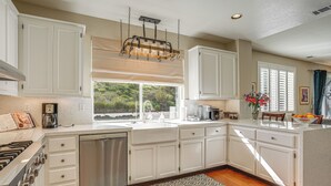 A modern kitchen with white cabinetry, a stainless steel dishwasher, and a large window providing a view of greenery outside. - Fairfield Wine Country Getaway w/ Backyard Oasis! (Fairfield)