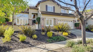 A two-story house with a garage, surrounded by landscaped garden beds and various shrubs. - Fairfield Wine Country Getaway w/ Backyard Oasis! (Fairfield)