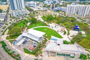 An aerial view of a modern building complex with a parking lot, green spaces, and surrounding high-rise buildings. - Elegant Condo w/ Stunning Views in Dtwn Hollywood (Hollywood)