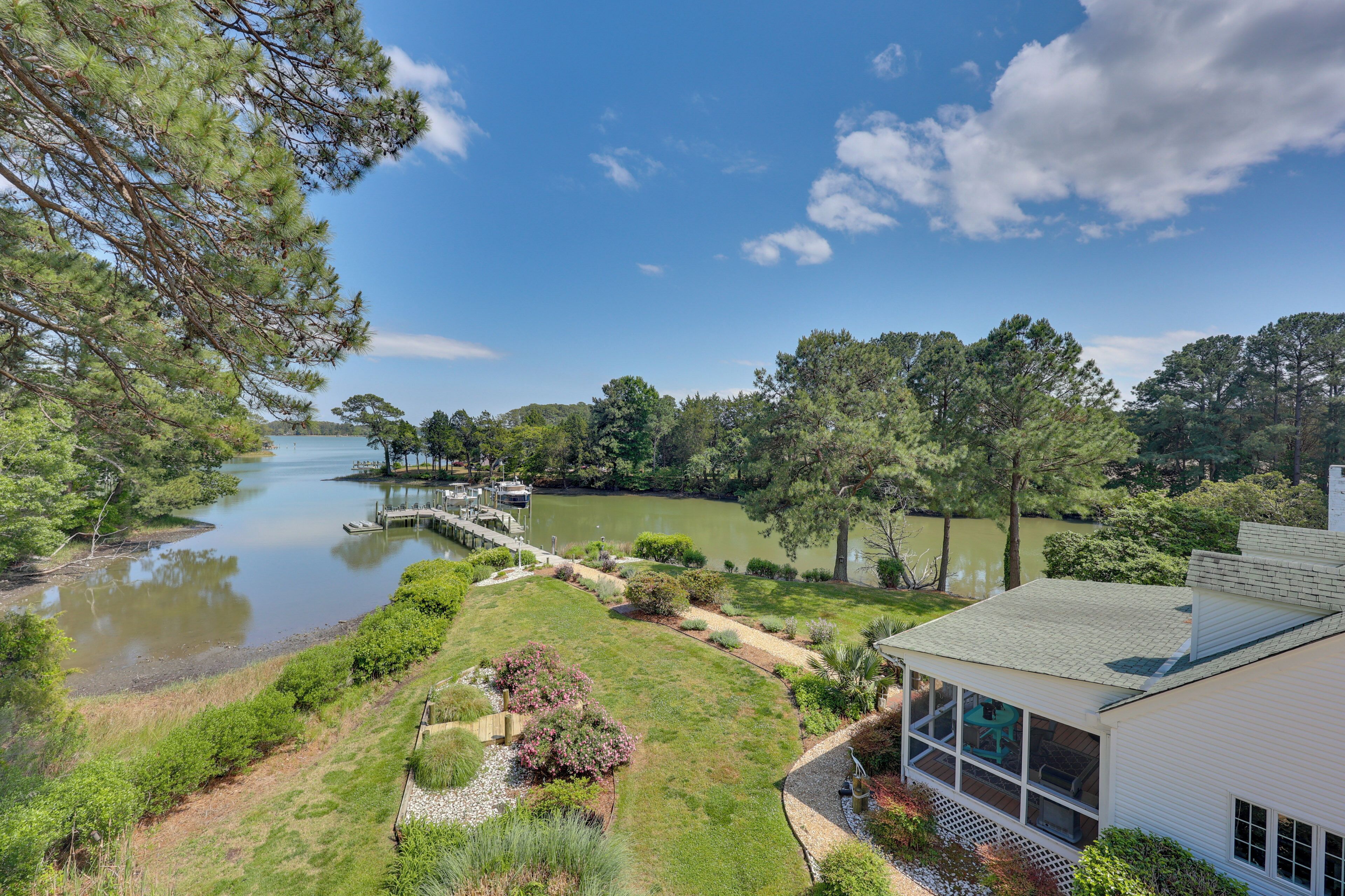 A lakeside property with a dock, a covered outdoor seating area, and a white building with large windows.