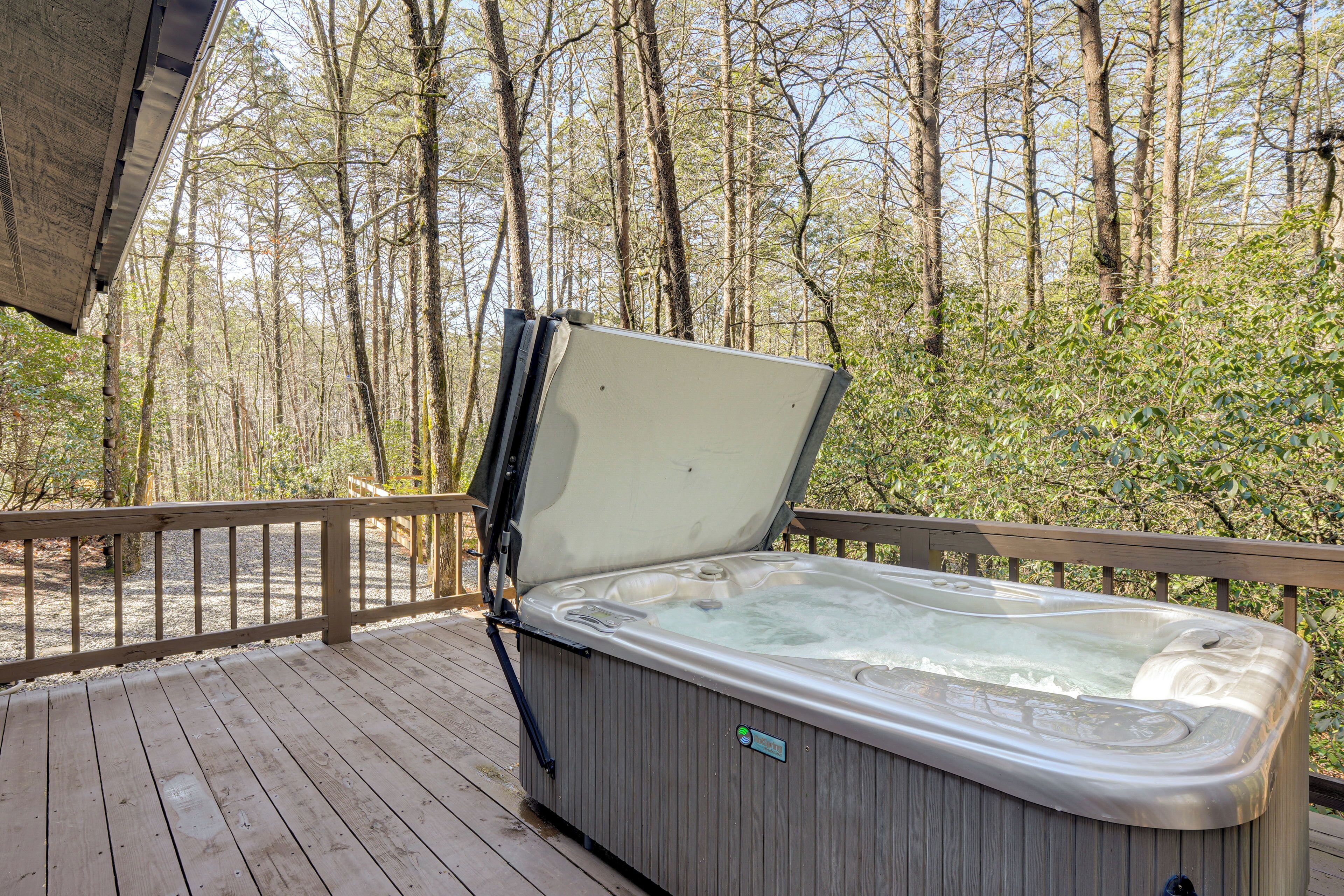 A hot tub on a wooden deck with a view of a forest.