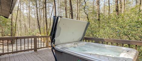 A hot tub on a wooden deck with a view of a forest.
