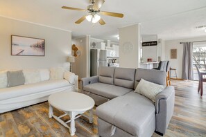 A modern living room with a white sofa, grey sectional, and a small white table. A ceiling fan and a painting are visible. - Lake Conroe Bliss: Waterfront Home w/ Boat Ramp (Willis)