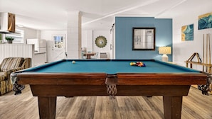 A pool table in a room with a blue accent wall, a white door, and a clock on the wall. - Perfect for Small Families, Steps to Beach and Dining by Tybee Cottages (Savannah)
