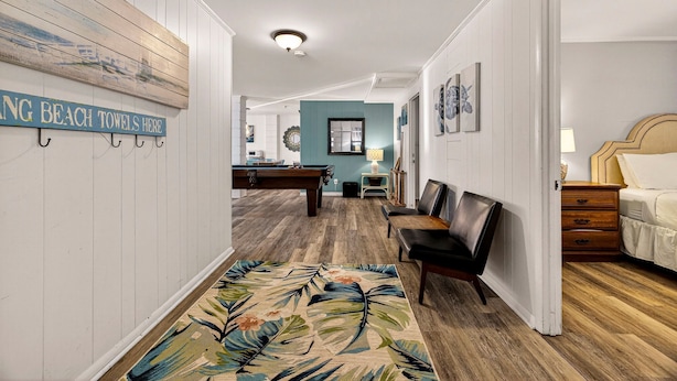 A hallway with a pool table, a teal accent wall, and a sign indicating beach towels are available. - Perfect for Small Families, Steps to Beach and Dining by Tybee Cottages (Savannah)