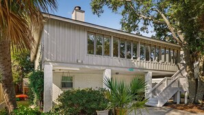 A two-story building with a covered porch, a staircase, and a brick facade. - Perfect for Small Families, Steps to Beach and Dining by Tybee Cottages (Savannah)