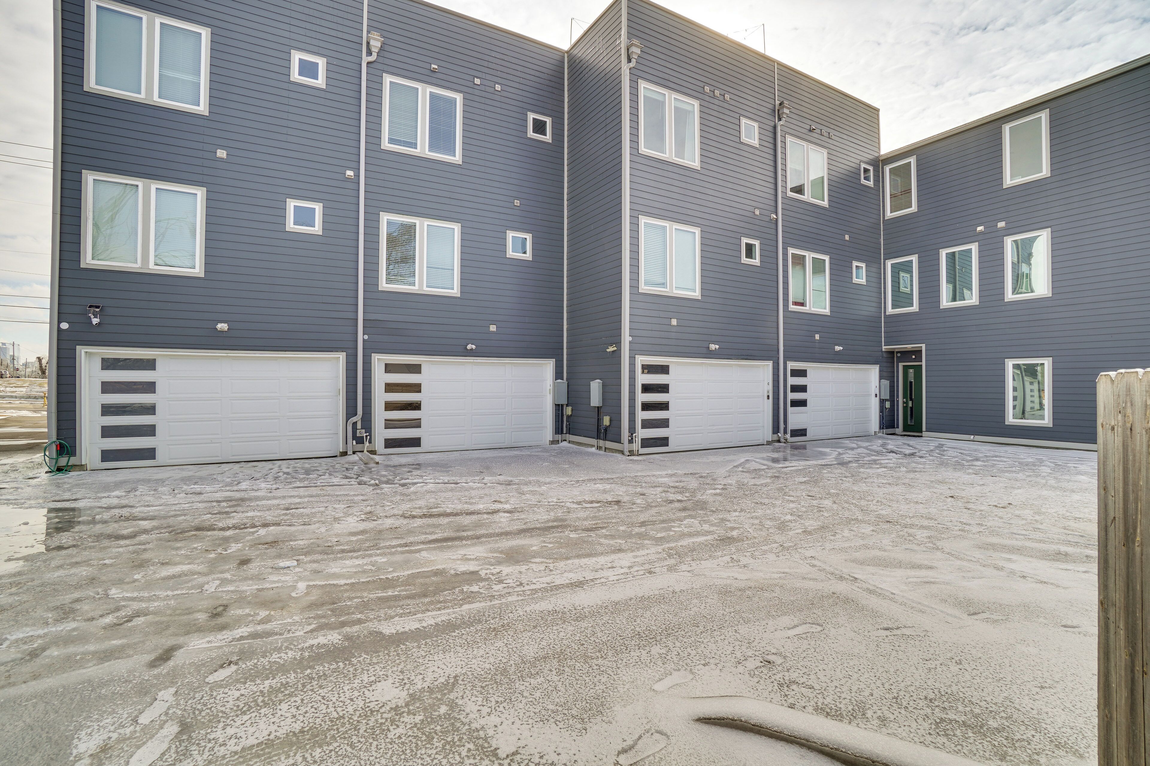 A multi-story residential building with a garage entrance and a concrete driveway.