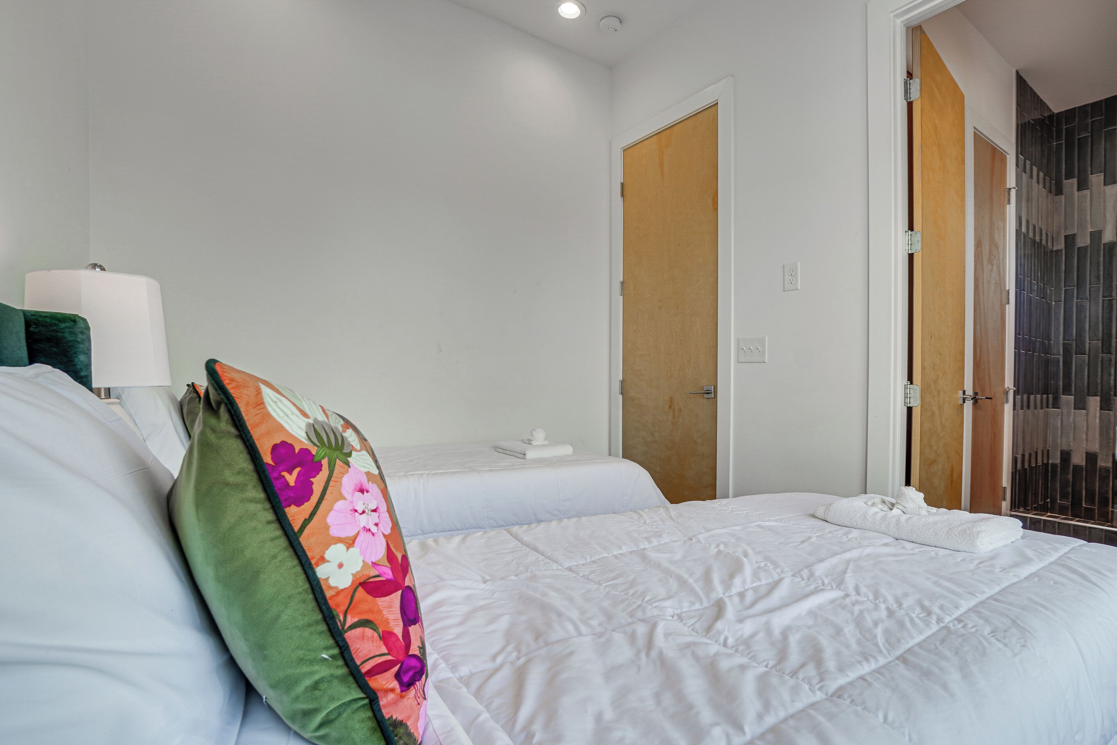 A hotel room with a large bed, a bedside table with a lamp, and a wooden door.